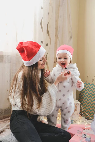 Святкування Різдва в новій нормі. Родина святкує Різдво під час пандемії COVID. Маленька дівчинка з мамою розважаються і лагодять одне одного вдома. — стокове фото
