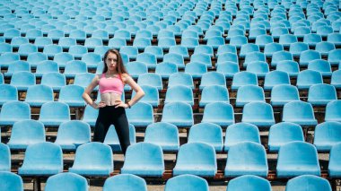 Açık hava fitness, antrenman, temiz hava sporu. Elinde su şişesi olan genç bir kadın atlayıp kaçıyor. Spor kıyafetli kız dışarıda egzersiz yapıyor..