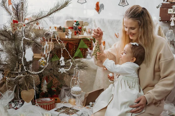 Різдвяні та зимові канікули. Новий 2021 рік прийде, Кози Крістмас Концепція. Маленька дівчинка з мамою прикрашають ялинку прикрасами і влаштовують вдома світло. — стокове фото