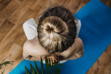 Evde yoga yaparken Lotus pozisyonunda oturan spor giysili genç bir kadının arka görüntüsü. Sırt egzersizleri, esneme, pilates, kas geliştirmek için en iyi sırt egzersizleri.,