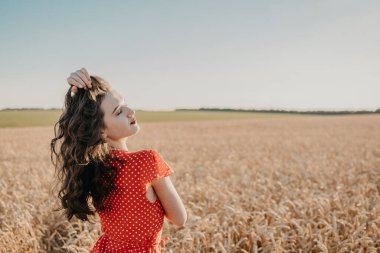 Doğal güzellik, doğaya duyarlılık, hayatın kutlanması küçük anlar konsepti. Buğday tarlasında güzel bir genç kadın. Gökyüzünde buğday tarlasında bir kadın