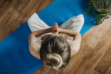 Öz-bakım, kendine şefkat, salgın sonrası dünyada zihinsel refah. Zihinsel sağlık, refah, endişeden kurtulmak için meditasyon. Yerde oturan genç kadın evde yoga ve meditasyon yapıyor.