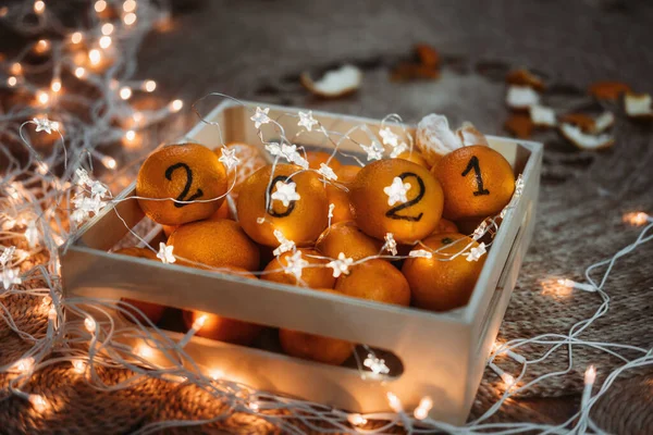 Christmas greeting card with oranges, tangerines with numbers 2021 and garland lights. New Year 2021 is Coming, Cozy Christmas Concept. Black Numbers 2021 written on Oranges — Stock Photo, Image