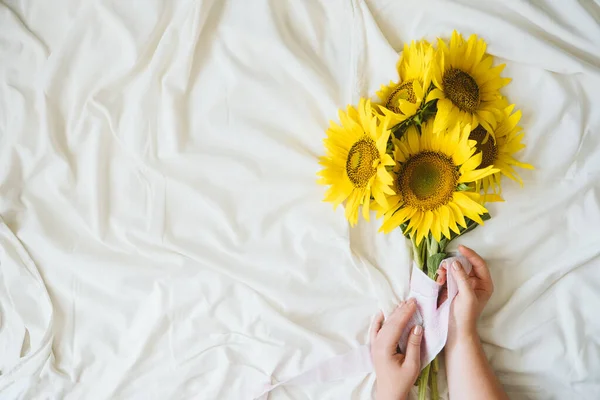 Candid auténtico ramo de girasoles amarillos sobre tela de fondo blanco. Fondo con ramo de girasoles amarillos sobre sábana blanca. Días soleados, concepto floral de verano — Foto de Stock