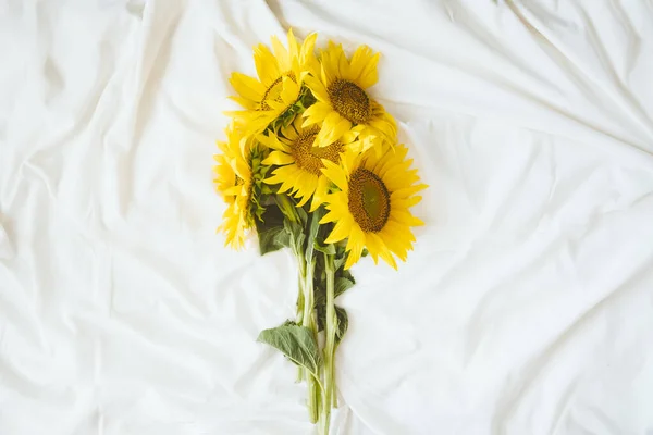 Candid authentic Yellow sunflowers bouquet on fabric white background. Background with bouquet of yellow sunflowers on white bed sheet. Sunny Days, Summer floral concept