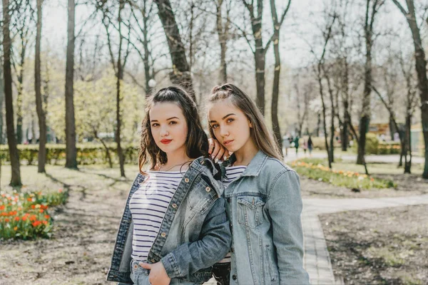 Gen z девушки наслаждаются на свежем воздухе, выражая положительные эмоции. Наружное фото двух подруг, веселящихся в парке. Две счастливые молодые женщины прыгают и смеются вместе — стоковое фото