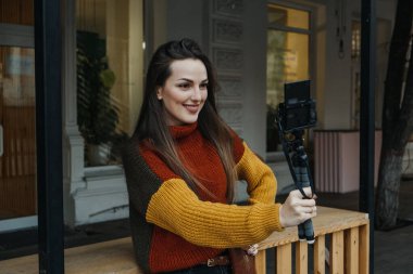 İçerik yaratıcısı, blogcu, vlogger genç kadın selfie çekiyor, kendini filme çekiyor ve şehir sokaklarında eğleniyor..