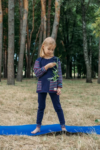 Environmental education for kids. Little girl holding young plant in hands against green tree background. Environment, sustainability, earth day, ecology concept