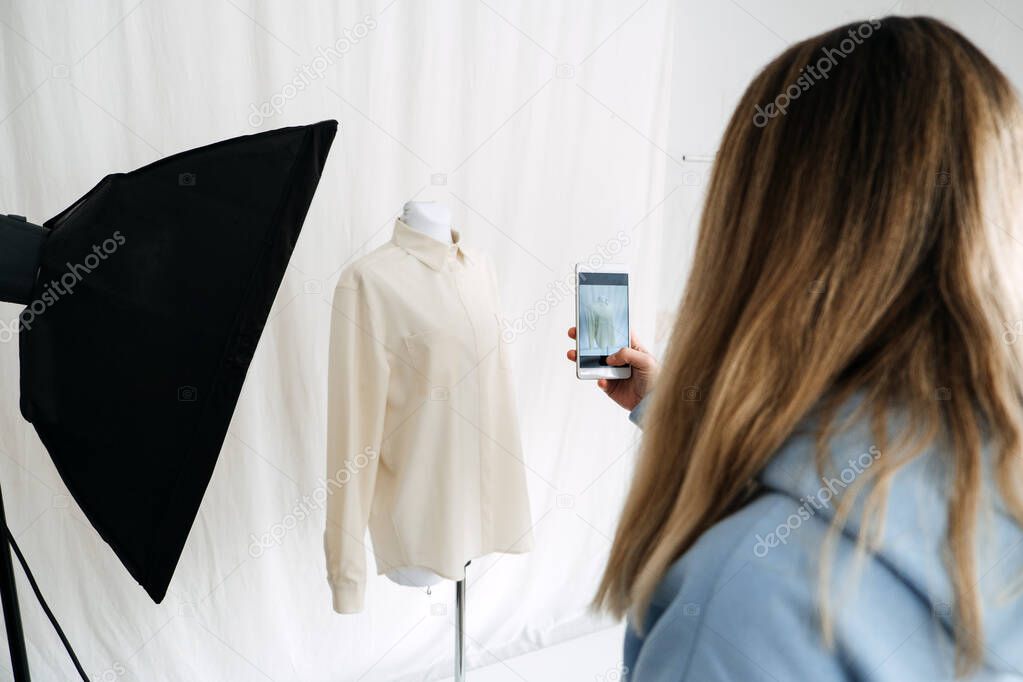 Circular Economy, Second hand, Fast fashion, Sustainable fashion. Shop owner taking pictures of Second hand clothes for online store sale.