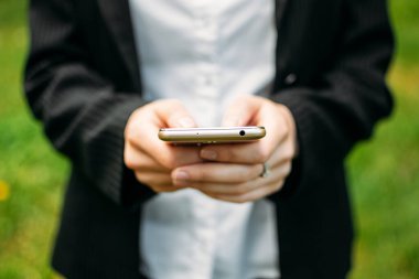 Kadın ellerini kapat ve cep telefonunu doğaya ver. Elde akıllı telefon resmi takım elbiseli kadın.