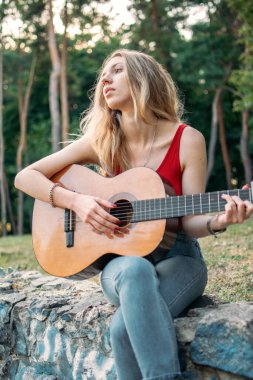 Yaratıcı hobiler, gitar dersleri, müzik aletleri çalmak. Yeni başlayanlar için akustik gitarlar. Akustik gitarlı genç sarışın kadın.