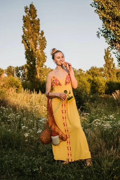 Zero waste life, eco friendly living, save nature, slow life. Young blonde happy woman with reusable cotton net bag with organic food on nature background