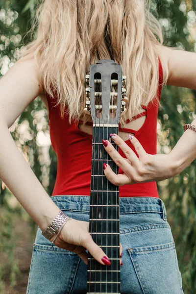 Creative hobbies, guitar lessons, playing musical instruments. Acoustic guitars for beginners. Young blonde woman with Acoustic guitar outdoor
