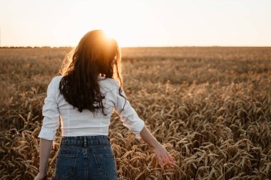 Kendine, motivasyona ve ilhama odaklan, her şeyi yeniden düşün, özgürlüğü. Mutlu genç kız güneş yaz gününde buğday tarlasında hayatın tadını çıkarıyor.