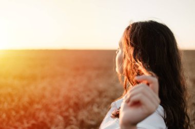Kendine odaklan, motivasyon ve ilham, her şeyi yeniden düşün, özgürlüğü. Genç esmer kız yaz günü günbatımı buğday tarlasında hayatın tadını çıkarıyor..