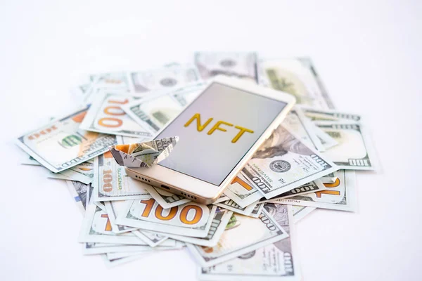 Finansal olmayan marka NFT, kripto sanat, dijital sanat, yeni tür şifreleme. Altın çerçeveli altın NFT metin ile cep telefonu dolar arkaplan üzerinde sanat nesnesi olarak