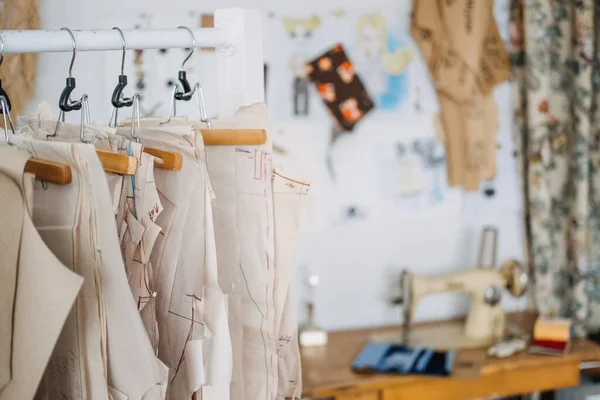 Mnoho papíru šití vzory pro různé oblečení visí na stojanu v šití tovární pozadí. Vzor oblečení, výroba na šicí továrně. Krejčovství, malý obchod — Stock fotografie
