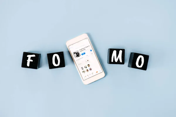 FOMO, Miedo a perderse, ansiedad social, permanecer continuamente conectado, miedo al arrepentimiento, Redes sociales. Texto FOMO con teléfono celular con iconos Clubhouse. Kropivnitskiy, Ucrania, 20 de marzo de 2021 — Foto de Stock