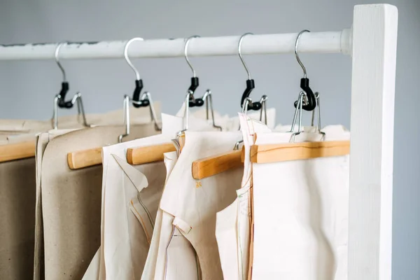 Muitos padrões de costura de papel para roupas diferentes penduradas no rack no fundo da fábrica de costura. Padrão de roupa, fabricação na fábrica de costura. Alfaiataria, pequenas empresas — Fotografia de Stock