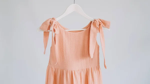 Muslin Eco Friendly Clothing, Organic Cotton Muslin Clothes. Natural tones dresses hanging on a hanger on white background