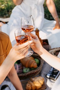 Yaz pikniği toplantıları, küçük grupların yaz partileri, yaz içkileri, küçük arkadaş toplantıları. Genç bayan kız arkadaşlar piknikte birlikte eğleniyorlar ve bardakla içki içiyorlar.