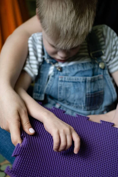 Juego sensorial para niños con necesidades especiales. Actividades para niños con discapacidad, Parálisis Cerebral. Niño con parálisis cerebral jugando con alfombra sensorial juego de masaje rompecabezas esteras para niños —  Fotos de Stock