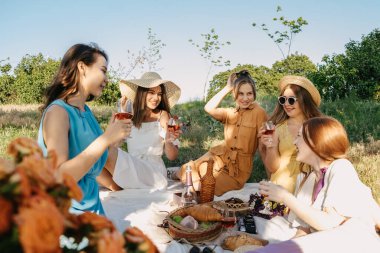 COVID Güvenli Yaz pikniği. Yaz Partisi Fikirleri. Küçük Ev Sahipliği İçin Güvenli ve Neşeli Yollar, Arkadaşlarla Açık Toplanma. İnsanlar güvenli bir şekilde bir araya geliyor. Piknikte genç bayan kız arkadaşlar.