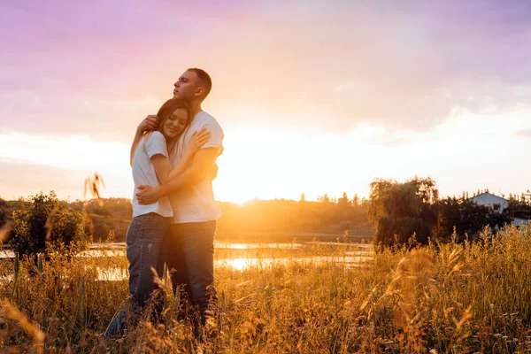 Escapada romántica, Destinos románticos a la luna de miel, viajes en solitario. Pareja en el amor silueta en la naturaleza puesta del sol amarillo y púrpura fondo del cielo. Pareja joven disfrutando de la puesta de sol en el prado. —  Fotos de Stock