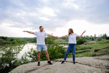 Bütçe Dost Canlısı Balayı İndirimleri, Romantik Kaçış, Yalnız Çiftler Seyahat. Birbirine aşık çiftler, beyaz tişörtlü yeni evliler, doğa konusunda eğleniyorlar. Genç çift yerel seyahatin tadını çıkarıyor
