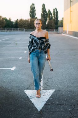 Kız gücü, feminizm, kendini savunan kadınlar. Açık havada beyzbol sopasıyla gezen kadın portresi. Genç kadın kendini savunuyor.