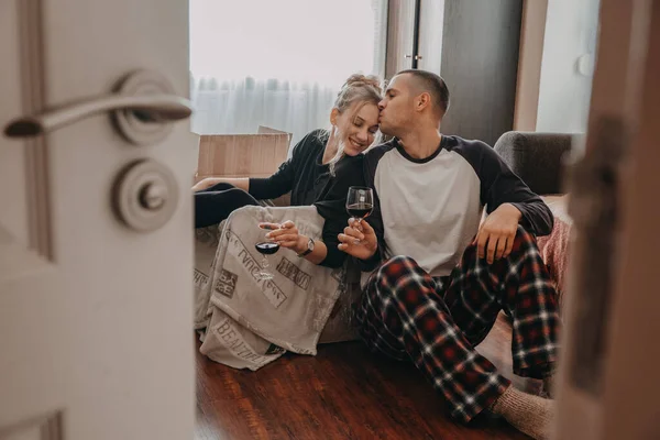 Día de celebración conmovedor. La pareja Yong se muda a un nuevo hogar. Joven pareja feliz, recién casados familia beber vino y divertirse en la habitación con cajas de cartón en un nuevo hogar —  Fotos de Stock