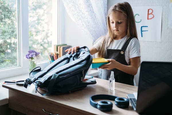 Zurück in die Schule, Schulkindhygiene, Sicherheitsvorkehrungen nach Coronavirus. Die Schülerin geht zur Schule und packt Lunchbox und Hand antiseptisch in Rucksack — Stockfoto