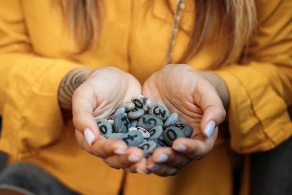 Numeroloji Sayıları Konsepti. Numeroloji Yaşam Yolunu ve Kader Numaralarını Hesapla. Kadın avuçlarında boyalı sayılar olan çakıl taşları.