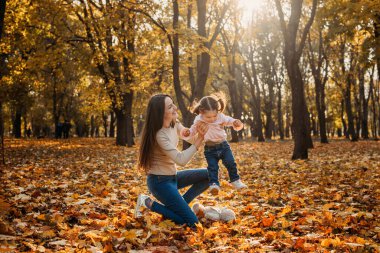 Mutlu aile annesi ve küçük bebek sonbahar parkında oynuyorlar. Küçük kız ve annesi sonbahar parkında. Bebekler için sonbahar etkinlikleri