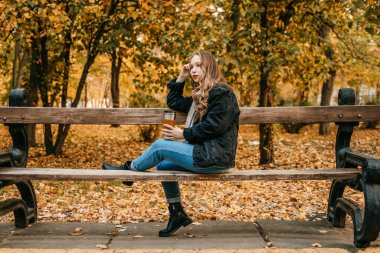 Sıfır Atık Düşme Faaliyetleri, Sonbahar sezonu için Yapılacak şeyler, Çevre dostu, Çevre dostu yaşam. Harika bir sonbahar sezonunun tadını çıkarıyorum. Yeniden kullanılabilir kahve fincanı olan genç ve güzel bir kadın sonbahar parkında yürüyor..