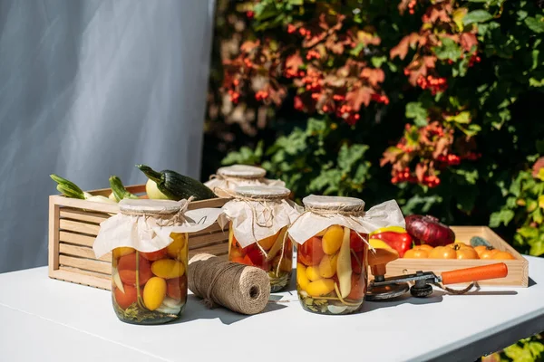 キャニングガーデン野菜,トマトの保存,ピーマン,ズッキーニの野菜.夏の日に庭のテーブルの上のガラス瓶に缶詰の野菜. — ストック写真