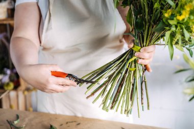 Çiçek atölyesinde buket buketi makasıyla buduyor. El yapımı çiçekçilik, sürdürülebilir çiçekçilik, küçük işletme yaratıcılığı, zanaatkar çalışma alanı. Yüksek kalite fotoğraf
