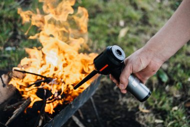 Açık havada taşınabilir hava üfleyicisi kullanarak metal bir ızgarada odun ateşi yakmak. Sonbahar barbekü sezonu, arka bahçede mangal, açık hava aşçısı yaşam tarzı, ateş çukuru tarifleri. Yüksek kalite fotoğraf