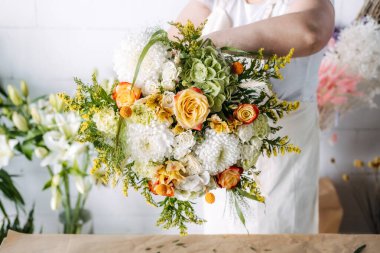 Bitmiş bir buketi turuncu, sarı ve beyaz mevsimlik çiçeklerle sunan çiçekçi. Sonbahar kutlaması, Şükran Günü çiçekleri, rahat hediyeler, sürdürülebilir el yapımı dekorasyon. Yüksek kalite fotoğraf
