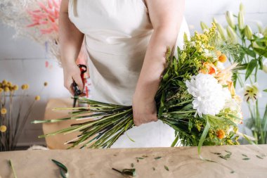 Çiçek atölyesinde buket buketi makasıyla buduyor. El yapımı çiçekçilik, sürdürülebilir çiçekçilik, küçük işletme yaratıcılığı, zanaatkar çalışma alanı. Yüksek kalite fotoğraf