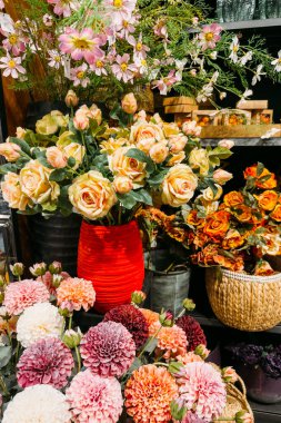 Suni güllerin, yıldız çiçeklerinin ve kozmosun renkli düzenlemeleri bir sergi rafında vazo ve sepetlerin içinde. Yapay çiçekler, yeniden kullanılabilir buketler, sürdürülebilir iç mekanlar, dekor uzun ömürlü. Yüksek kalite