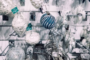 Perakende duvarda asılı çeşitli gümüş, beyaz ve mavi Noel süsleri. Maximalist ağaç dekoru, buzlu dokular, şenlikli süslemeler. Varşova, Polonya, 20 Kasım 2024.