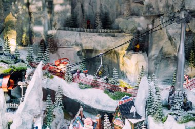 Minyatür kış kayak merkezi sahnesi, tramvaylı, karlı dağlar, çam ağaçları ve detaylı tatil vitrinli kayak okulu binası. Noel köyü dekoru. Varşova, Polonya, 20 Kasım 2024.