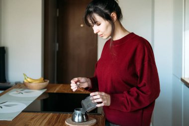 Kadın, kahve telvesini ahşap tezgahtaki kahve demliğine boşaltıyor. Kalp dostu bira, herkese kahve, kafein kültürü.