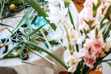 Large green hosta leaves and pink asters sit inside stone urn on work table with floral tools. Floral workshop, professional florist at work, seasonal botanical art