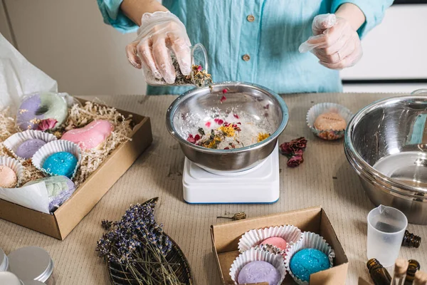 Eldivendeki eller cam şişeden metal kaseye dijital ölçekte botanik karışım döker. Küçük seri üretim, zanaatkar kozmetik ürünleri, bağımsız güzellik markası, kozmetik formülü