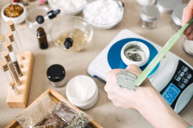 Duyusal geri bildirim için spatulayla cilde kozmetik ürün uygulayan kişinin eli. Doku analizi, ürün denemesi, kozmetik değerlendirme