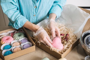 Eller, hediye kutularıyla çevrili dijital ölçekte metal kaseye botanik karışım döker. Nöro-Atmosferik Banyo, kortizol kurtarma, terpene banyosu, stres atma