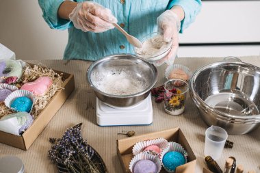 Dijital ölçekteki metal kasede kurutulmuş lavanta ve cam kavanozların yanında toz malzemeler var. Çiğ kozmetik malzemeler, botanik dokular, bitkisel cilt bakımı