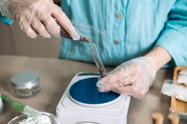 Eldivenli eller plastik paketten siyah botanik tuzu dijital ölçekte cam test tüpüne döker. Botanik katman, çok tuzlu boya, bitkisel zerk aşısı, estetik banyo tuzu.